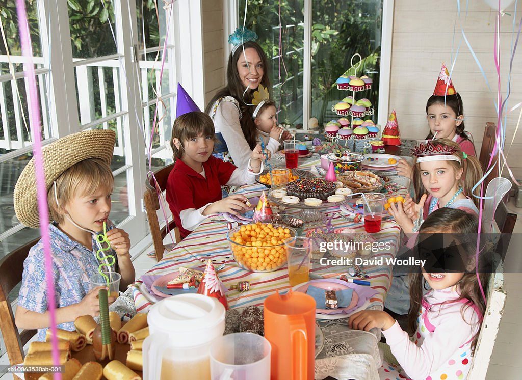 Young woman with group of children (2-7) sitting at table, elevated view