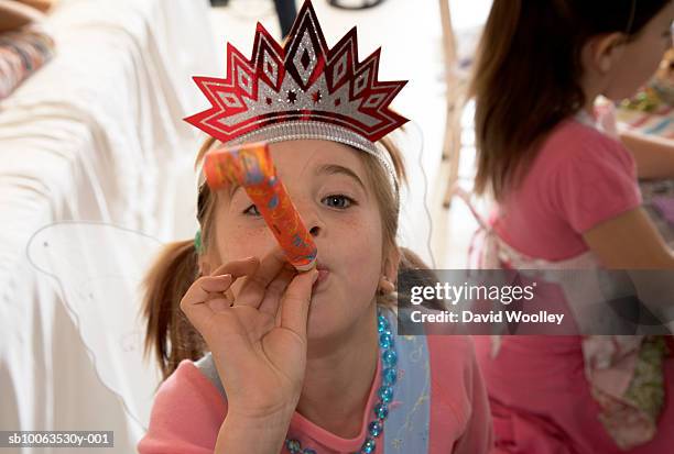 girl (6-7) in party hat blowing party horn blower, elevated view - party blower stock-fotos und bilder