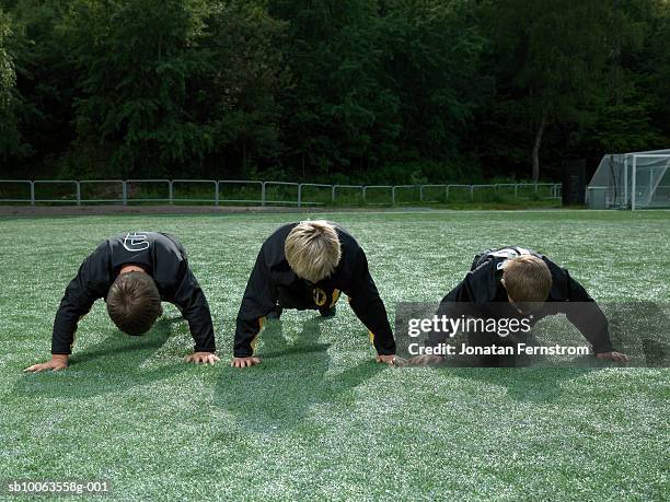 three boys (9-10 years) doing push ups on soccer field - 10 11 years boy stock pictures, royalty-free photos & images