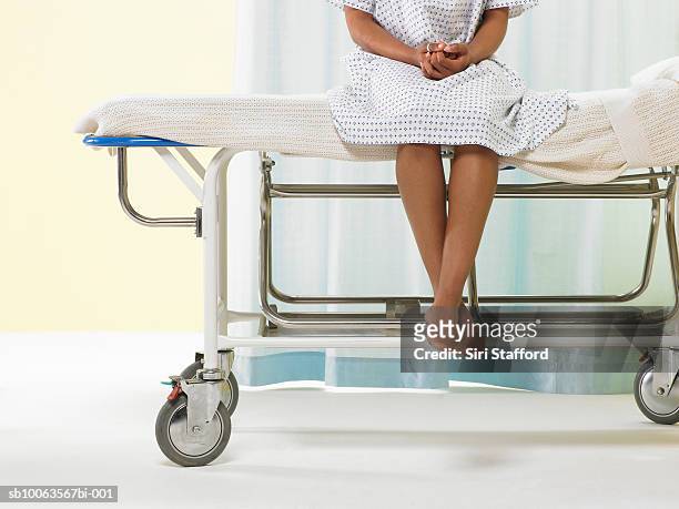 female patient sitting on gurney in hospital gown, low section - hospital gurney stock pictures, royalty-free photos & images