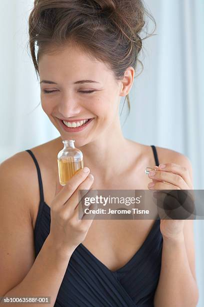 young woman smelling perfume, smiling - perfume stock pictures, royalty-free photos & images