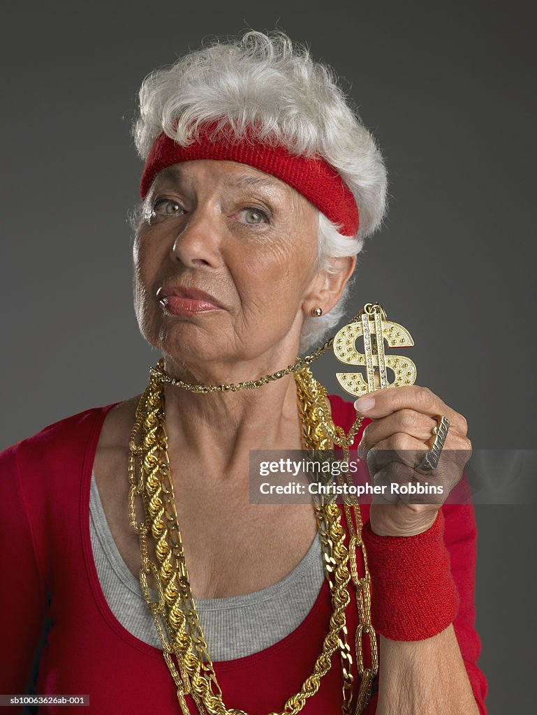 Senior woman wearing gold chains, holding dollar symbol
