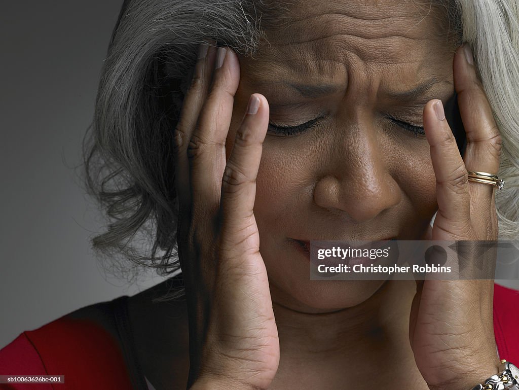 Mature woman with head in hands and eyes closed, close-up