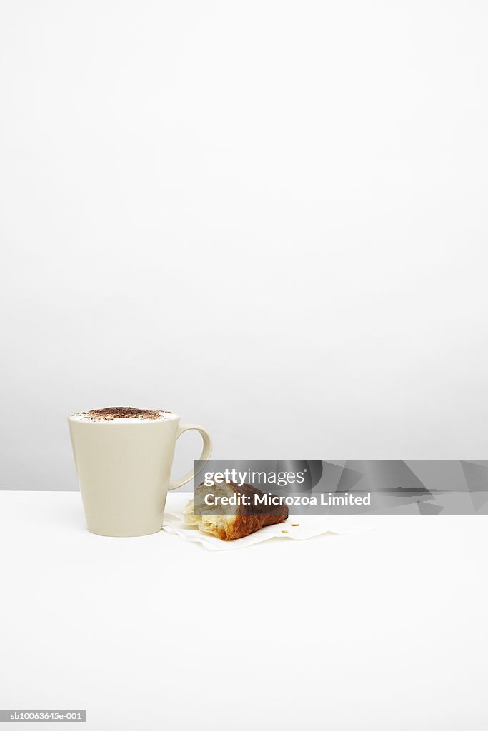 Cappuccino with croissant on table