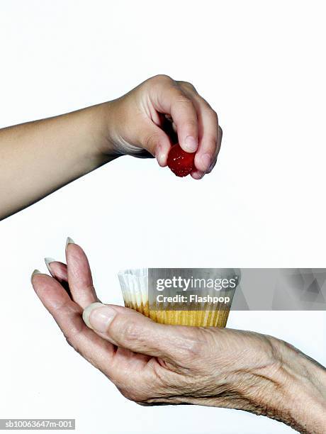 grandmother holding cupcake and granddaughter (8-9) putting cherry on it, close-up - holding kid hands stock pictures, royalty-free photos & images