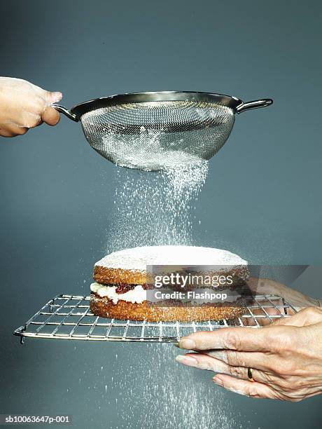 grandmother holding cake granddaughter (6-7) sieving sugar, close-up - powdered sugar stock pictures, royalty-free photos & images