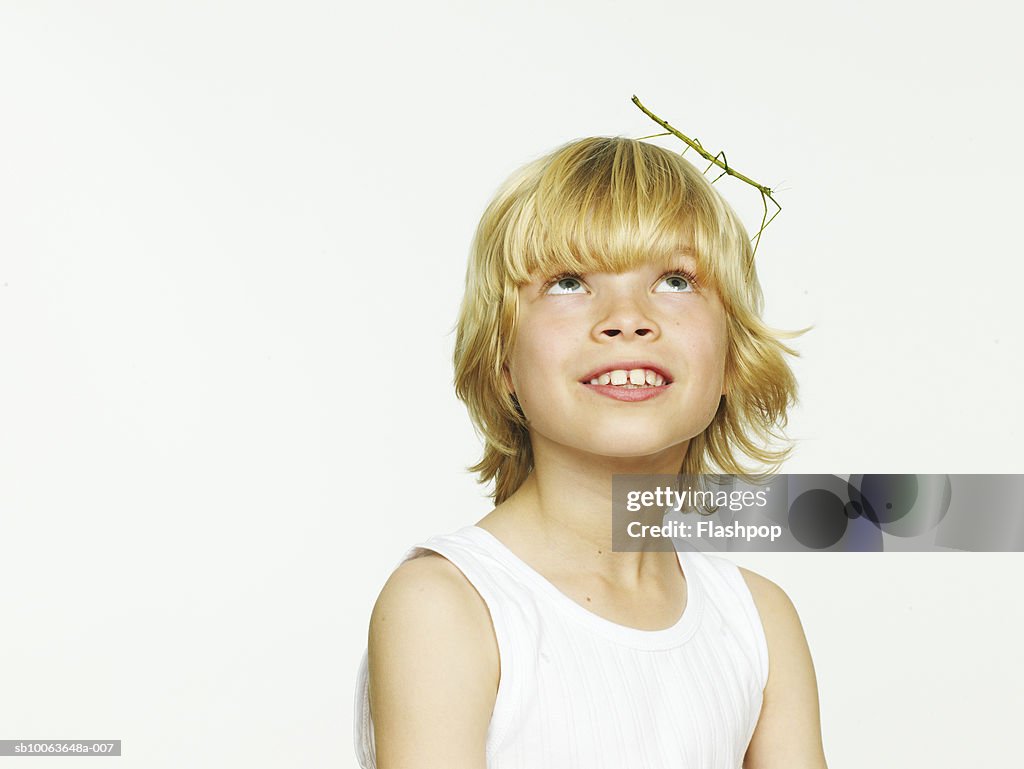 Boy (8-9) with grasshopper on head, close-up