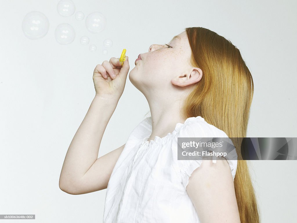 Girl (8-9) blowing bubbles, close-up