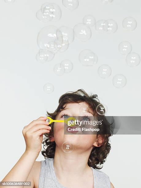 boy (6-7) blowing bubbles, close-up - child blowing bubbles stockfoto's en -beelden