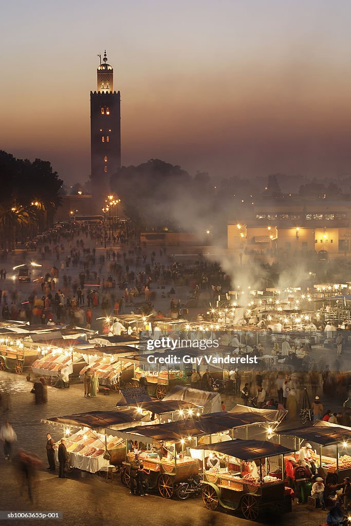 Morocco, Marrakesh, illuminated Djemaa el Fna square at night, Koutoubia Mosque in background