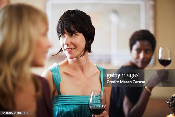 three friends tasting wine at bar, focus on woman in middle - wine bar stock pictures, royalty-free photos & images