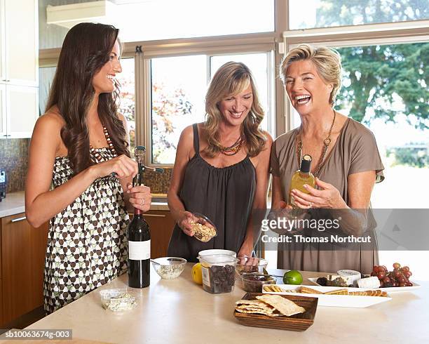 three women preparing hors d'oeuvres in kitchen, smiling - grupo pequeno de pessoas - fotografias e filmes do acervo