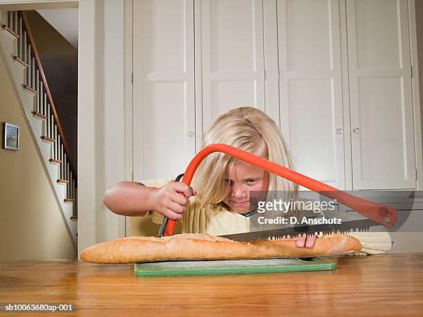 young girl (8-9) cutting baguette with hack saw - slash 2007 stock pictures, royalty-free photos & images