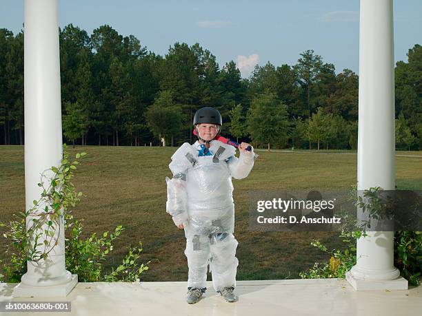 boy (10-11) wrapped in bubble pack, standing on porch with baseball bat - rausch stock-fotos und bilder