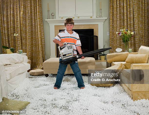 boy (10-11) holding leaf blower standing in pile of packing peanut in living room, portrait - misbehaviour fotografías e imágenes de stock