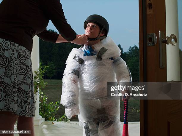 mother putting helmet on son's (10-11) head wrapped in bubble wrap - protección fotografías e imágenes de stock