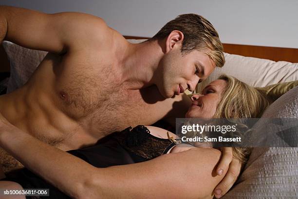 young man and mature woman lying on sofa, smiling - passie stockfoto's en -beelden