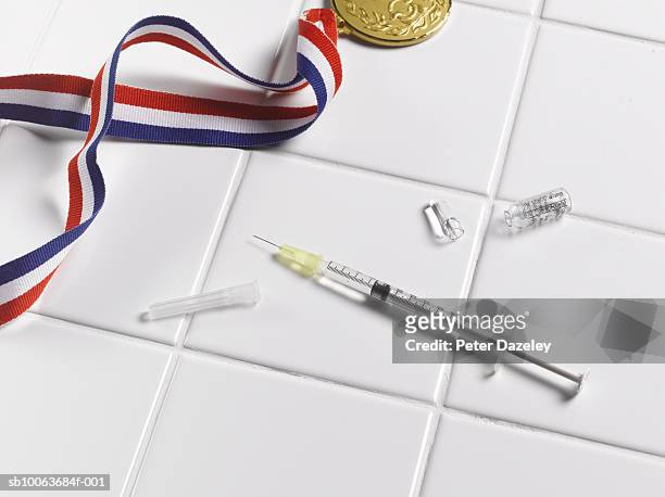 . medal and syringe on tiled floor - doping fotografías e imágenes de stock