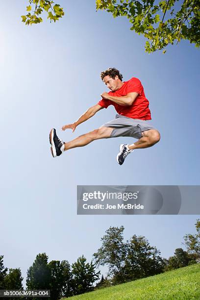 man kicking in mid-air, low angle view - martial arts man stock pictures, royalty-free photos & images