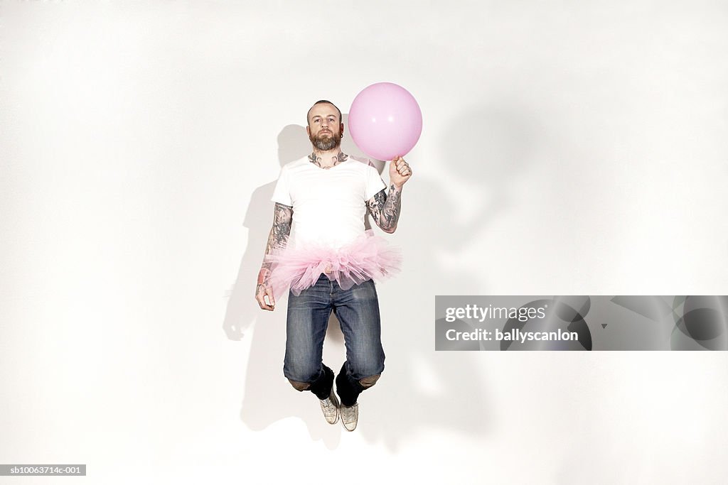 Man wearing tutu and holding balloon, portrait