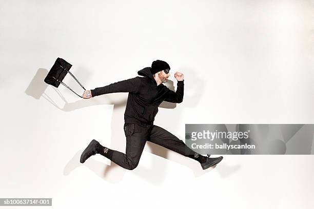 man running mid-air with handbag, side view - robbery stock-fotos und bilder