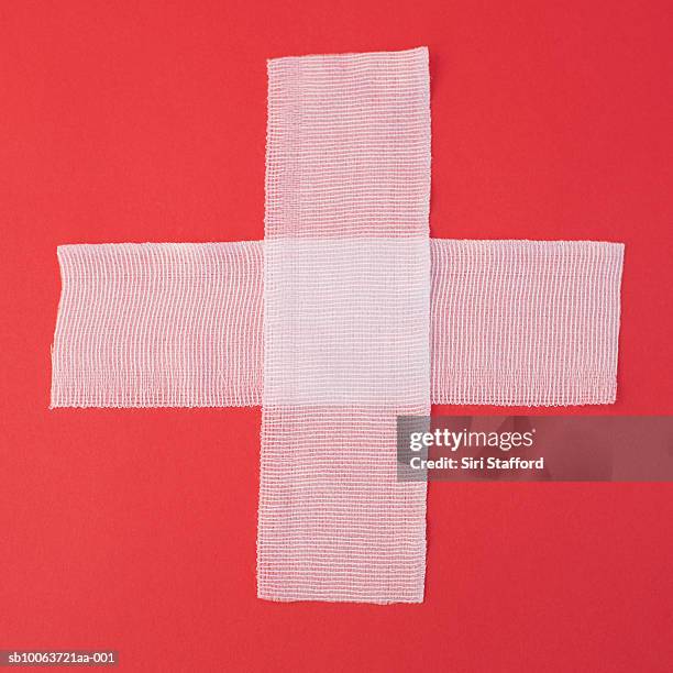 two sheets of gauze forming cross on red background, overhead view - gauze stock-fotos und bilder