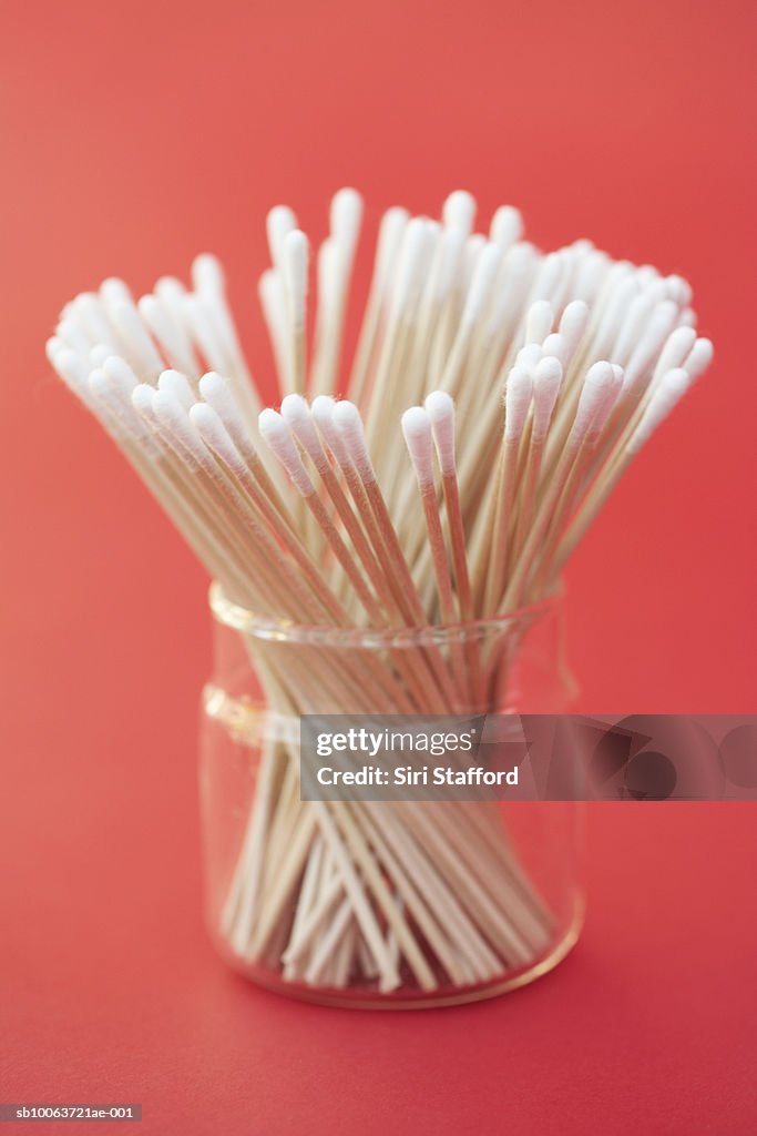 Jar of cotton swabs on red background