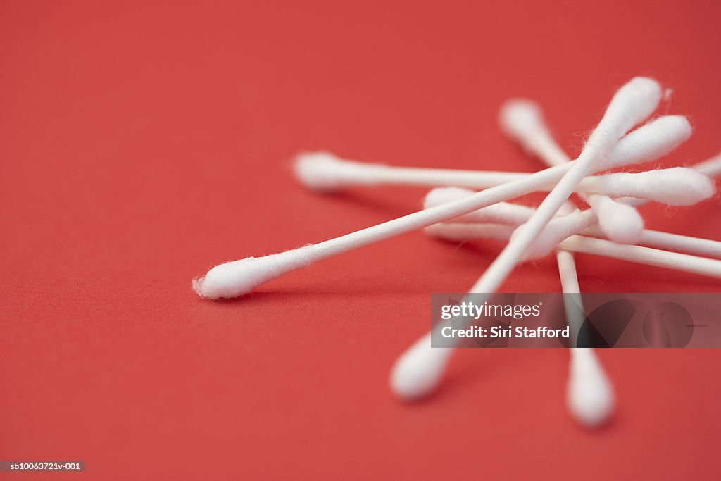 Cotton swab on red background, close-up (differential focus)