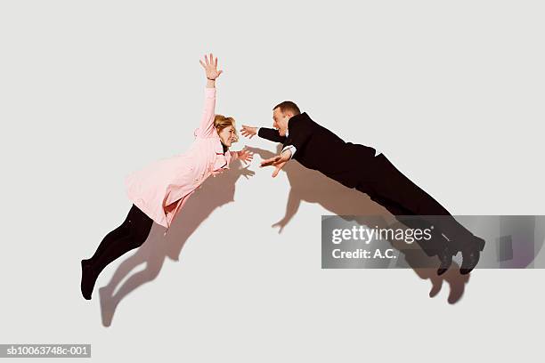 couple in mid air against white background, side view - オーバーコート ストックフォトと画像