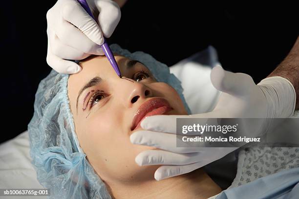 preparing woman in surgical gown for face lift - plastische chirurgie stock-fotos und bilder