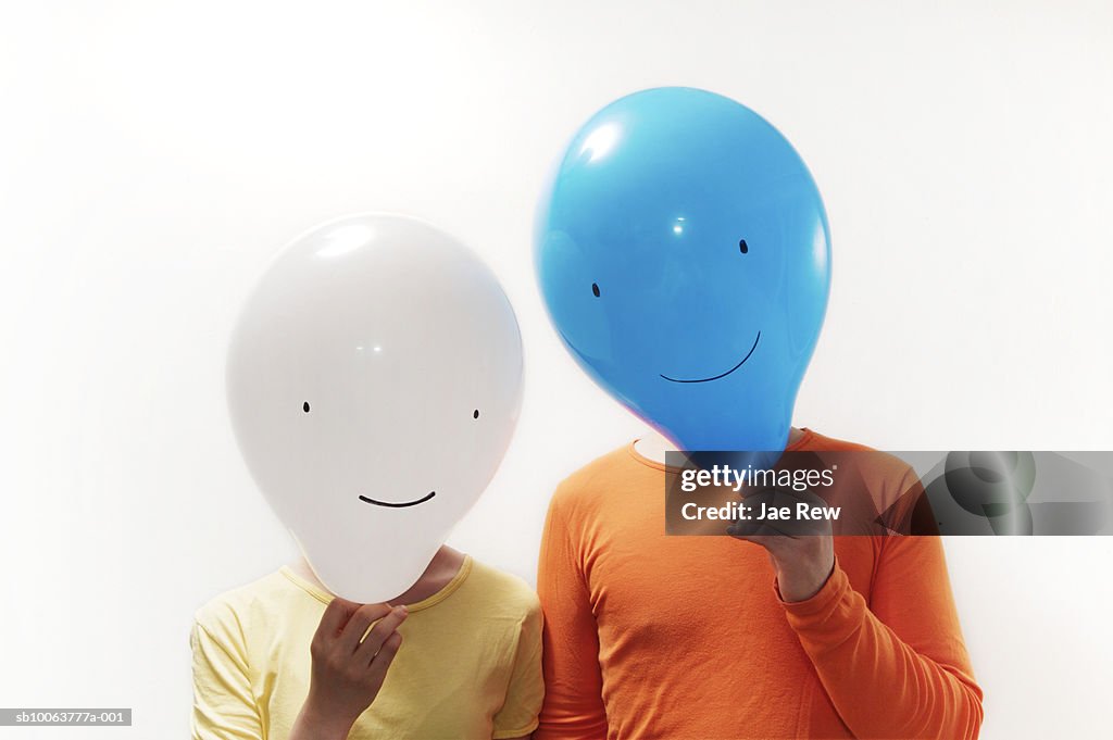 Man and woman with faces obscured by faced balloons