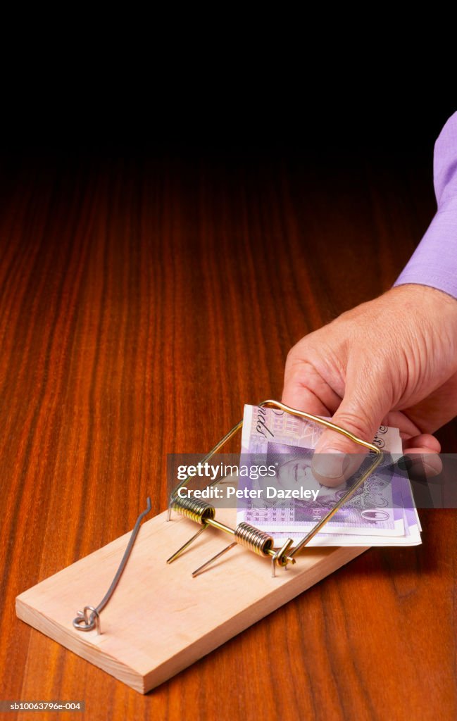 Man holding twenty pound notes in mouse trap, close-up