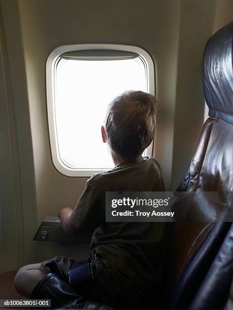 boy (4-5) looking out of aeroplane window - airplane seat back stock pictures, royalty-free photos & images