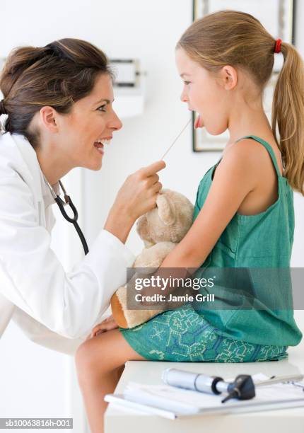 paediatrician checking girl (6-7)  with tongue depressor - girl tongue doctor stockfoto's en -beelden