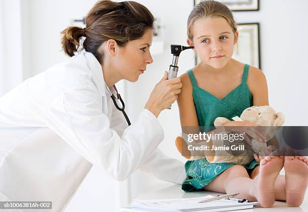 paediatrician examining girl's (6-7) ear with otoscope - otoscope foto e immagini stock