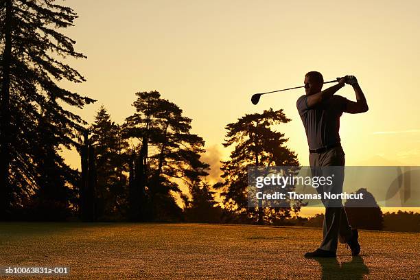 golfer swinging club on golf course at sunset - golf clubs stock pictures, royalty-free photos & images