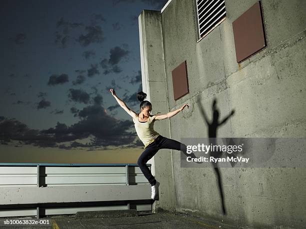 woman jumping mid air on rooftop carpark - dança moderna imagens e fotografias de stock