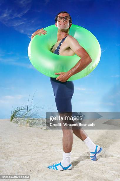 man holding inflatable ring on beach - mens swimwear foto e immagini stock