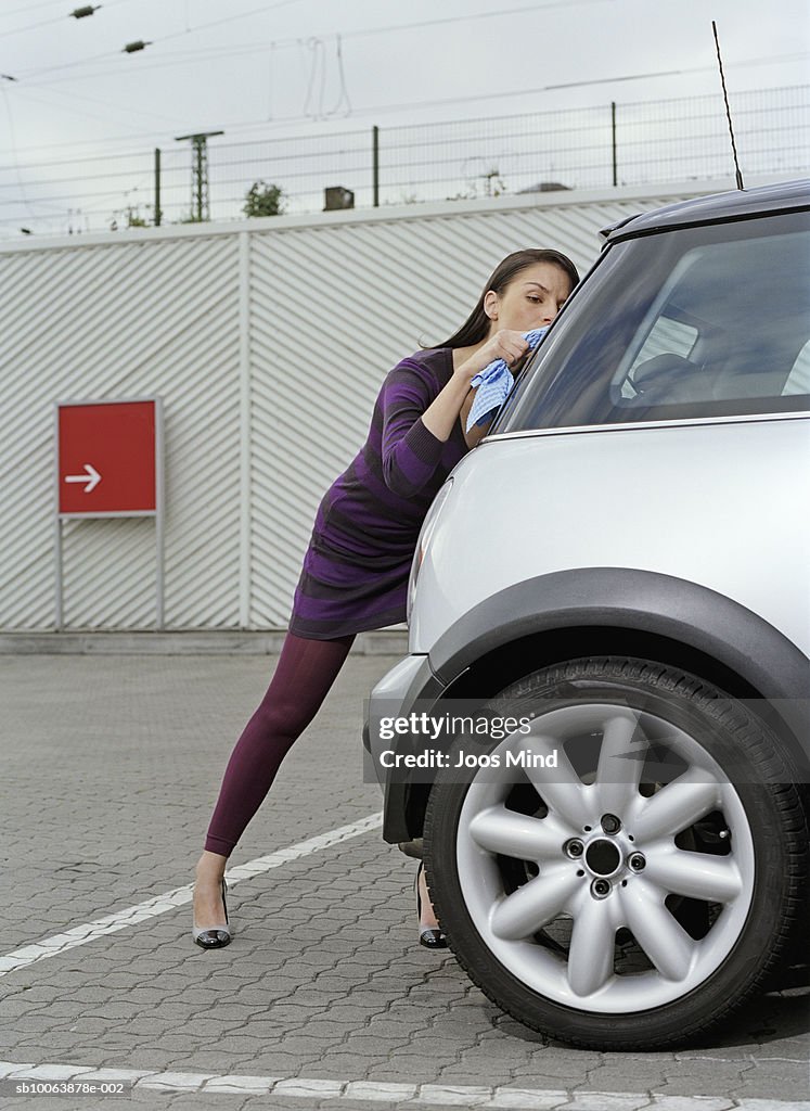 Young woman at petrol station polishing car window
