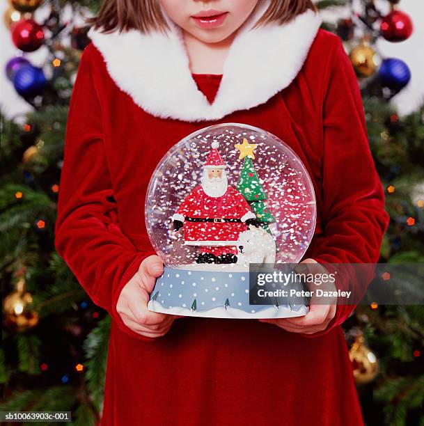 girl (6-7 years) holding snow globe in front of christmas tree, mid section - kitsch stock pictures, royalty-free photos & images