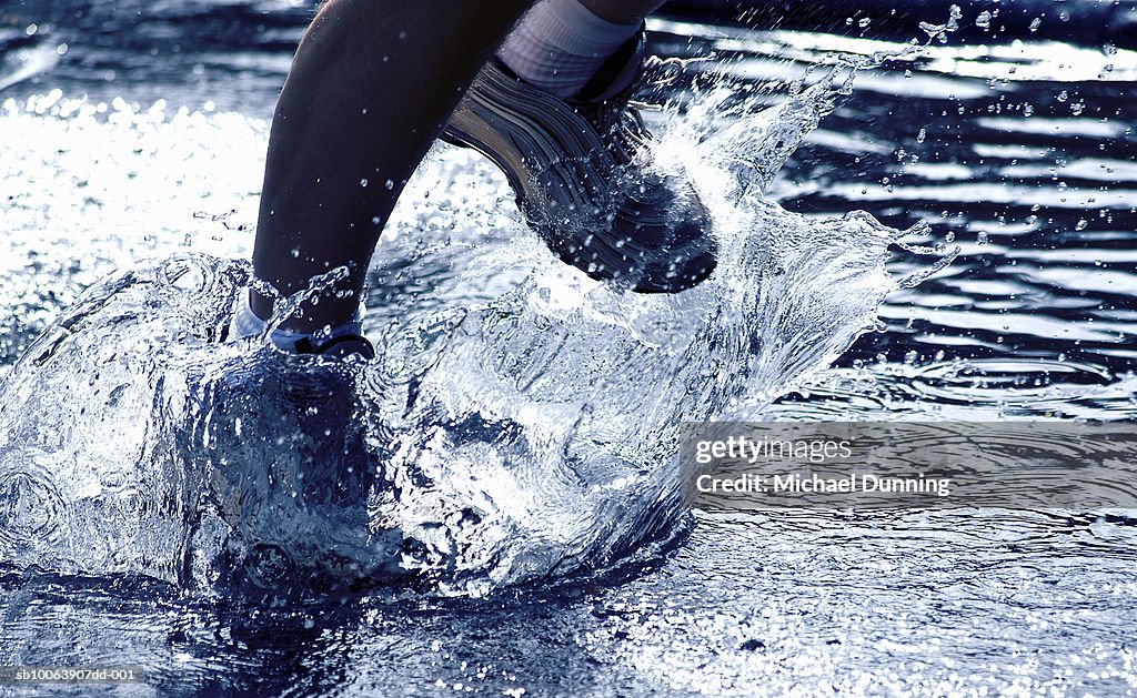 Athlete running through water, low section