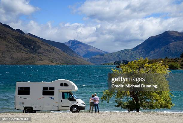 couple outside camper looking at lake - campervan stockfoto's en -beelden