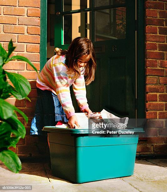 girl (6-7) putting out newspapers in recycling box - mixed recycling bin stock pictures, royalty-free photos & images