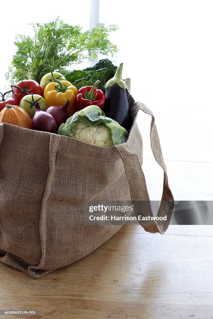 Eco friendly shopping bag filled with vegetables on table