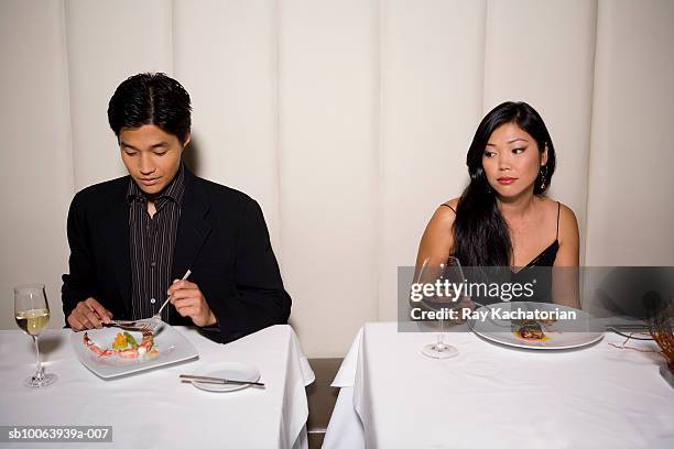 woman watching man eating in restaurant - asian couple dinner stock pictures, royalty-free photos & images