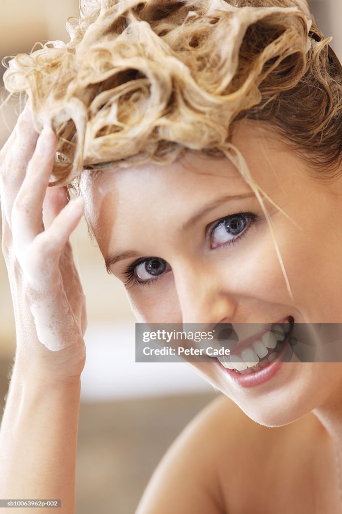 Young woman washing hair, smiling, portrait, close-up