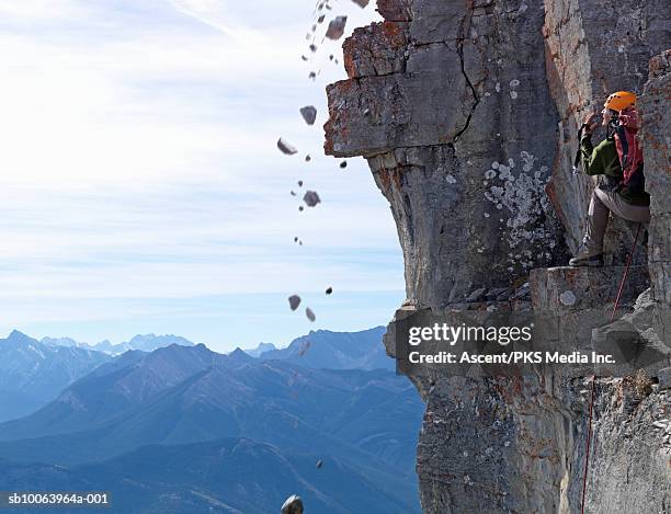 man climber standing on rock, looking at falling stones - fels stock-fotos und bilder