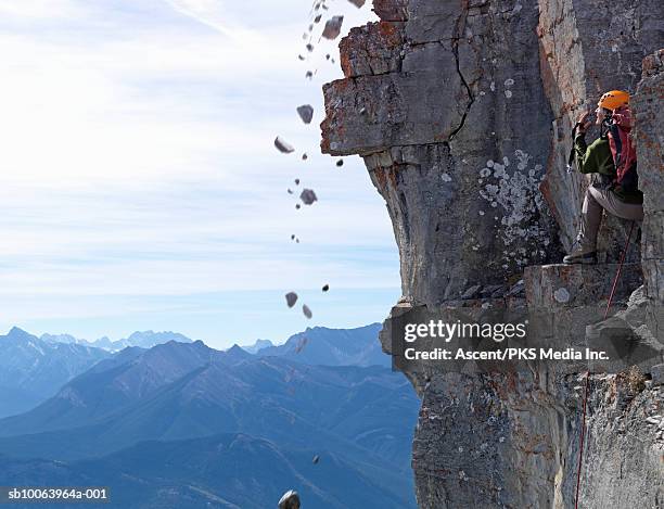 man climber standing on rock, looking at falling stones - rocky mountaineer stock pictures, royalty-free photos & images