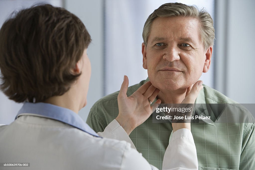 Female doctor examining male patient's throat