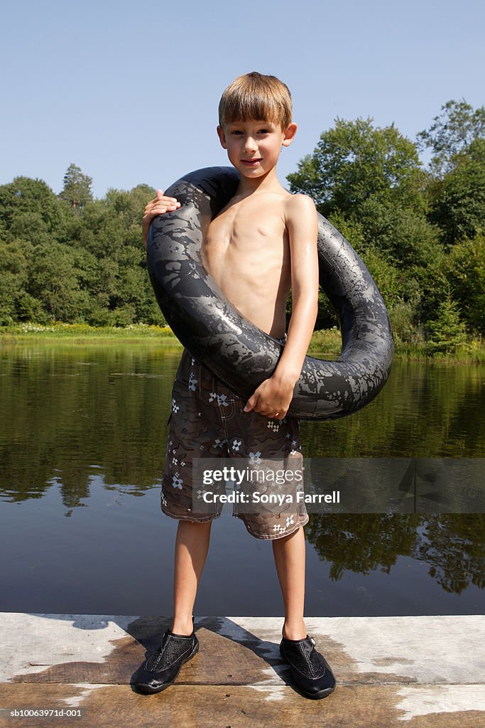 Boy (4-6) on jetty, with inner tube around neck, portrait